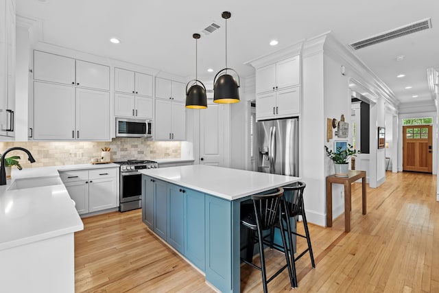 1603 Columbia St, Houston, TX 77008 - kitchen featuring appliances with stainless steel finishes, a center island, decorative backsplash, recessed lighting, and light wood-style flooring