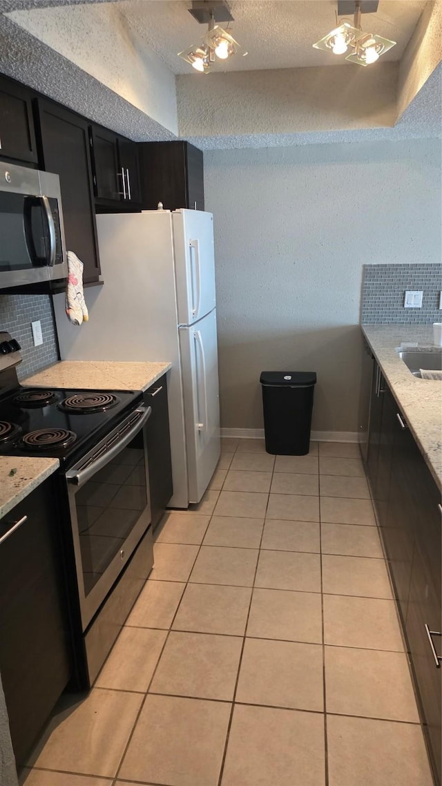 2818 S Bartell Dr Unit 13, Houston, TX 77054 - kitchen featuring stainless steel appliances, dark cabinetry, backsplash, light tile patterned flooring, and light stone countertops