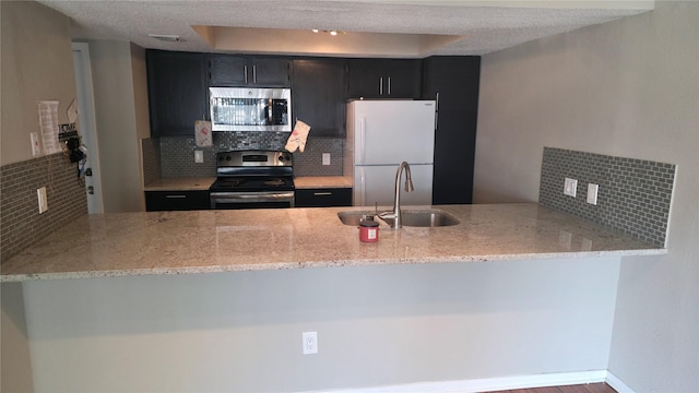 2818 S Bartell Dr Unit 13, Houston, TX 77054 - kitchen with stainless steel appliances, a peninsula, backsplash, light stone counters, and dark cabinetry