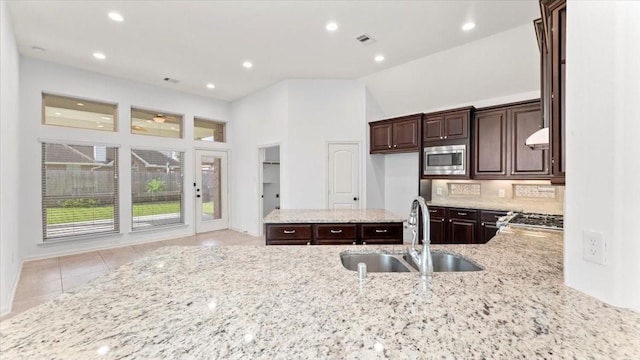 4627 Western Brook Dr, Spring, TX 77388 - kitchen featuring stainless steel microwave, light stone countertops, dark brown cabinetry, recessed lighting, and light tile patterned flooring