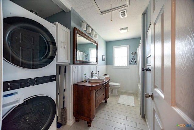 40 Sailfish Lndg, Port Lavaca, TX 77979 - laundry area with stacked washer and clothes dryer, attic access, wainscoting, and light tile patterned floors