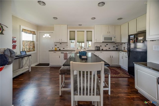 40 Sailfish Lndg, Port Lavaca, TX 77979 - kitchen featuring freestanding refrigerator, white microwave, dark countertops, decorative backsplash, and a kitchen island