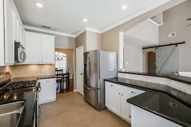 3817 Dunlavy Dr, Pearland, TX 77581 - kitchen with a barn door, appliances with stainless steel finishes, backsplash, white cabinetry, and crown molding