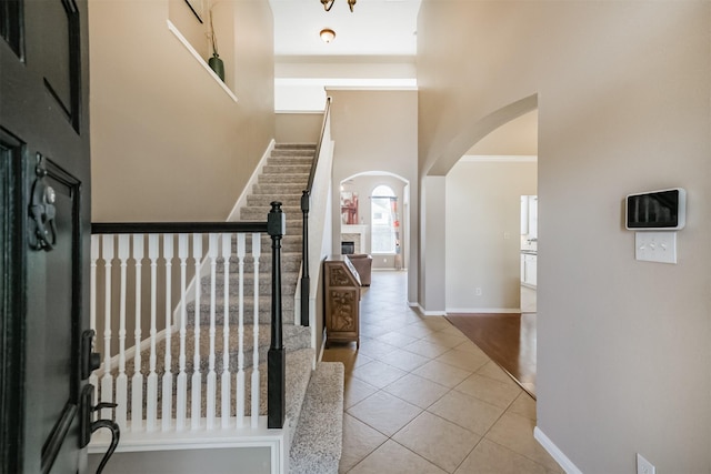 3817 Dunlavy Dr, Pearland, TX 77581 - tiled entryway featuring arched walkways, stairway, a high ceiling, and a fireplace