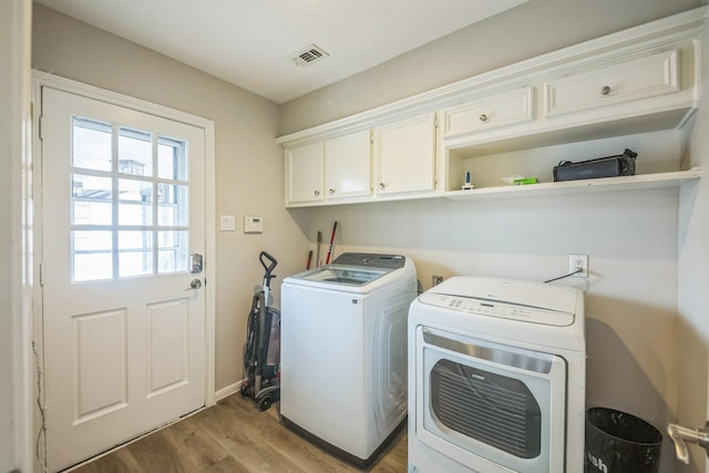 18318 Widcombe Dr, Houston, TX 77084 - laundry area featuring washing machine and dryer, cabinet space, and light wood-style flooring