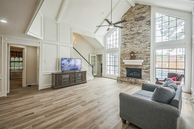 18318 Widcombe Dr, Houston, TX 77084 - living room featuring stairway, ceiling fan, high vaulted ceiling, a decorative wall, and light wood finished floors