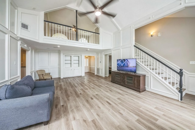 18318 Widcombe Dr, Houston, TX 77084 - living area featuring a decorative wall, a ceiling fan, light wood-type flooring, stairway, and high vaulted ceiling