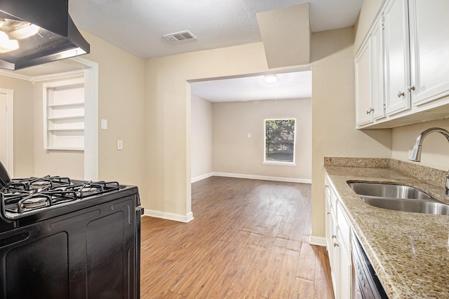 5235 Kingsbury St, Houston, TX 77021 - kitchen with wall chimney range hood, black gas range, light wood finished floors, white cabinets, and light stone countertops