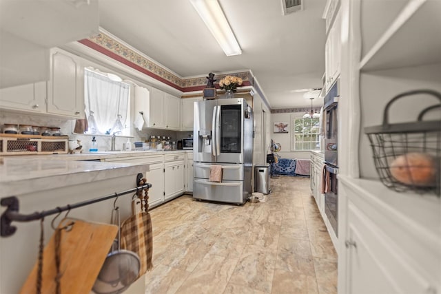 907 E Houston Ave, Crockett, TX 75835 - kitchen with stainless steel appliances, light countertops, white cabinetry, ornamental molding, and decorative backsplash
