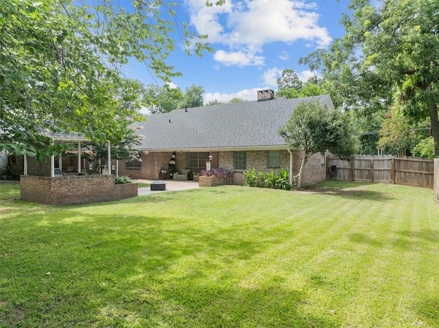 907 E Houston Ave, Crockett, TX 75835 - back of property with a patio, brick siding, roof with shingles, and a chimney