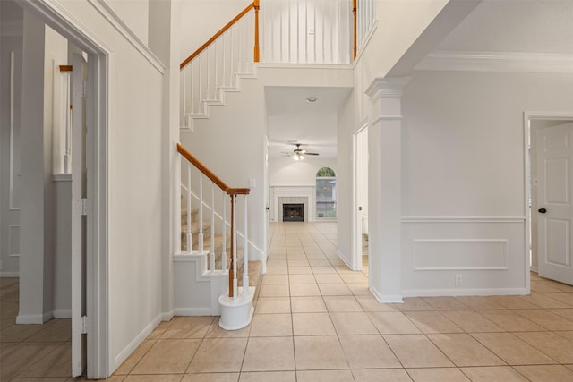 107 N Sunny Slope Cir, The Woodlands, TX 77381 - foyer entrance featuring stairs, light tile patterned flooring, a ceiling fan, crown molding, and a towering ceiling
