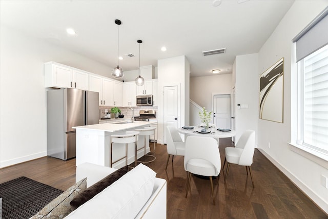 4155 Griggs Rd, Houston, TX 77021 - kitchen featuring stainless steel appliances, an island with sink, tasteful backsplash, dark wood-type flooring, and light countertops