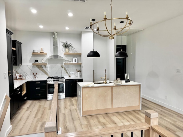 308 E 36th St, Houston, TX 77018 - kitchen with gas stove, wall chimney exhaust hood, dark cabinets, open shelves, and light wood finished floors
