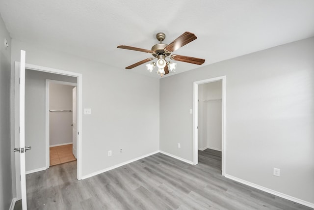 10342 Whisper Bluff Dr, Humble, TX 77396 - unfurnished bedroom featuring a walk in closet, wood finished floors, and a ceiling fan