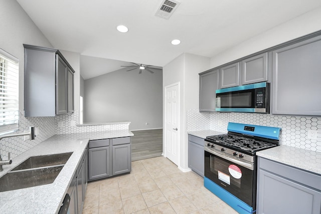 10342 Whisper Bluff Dr, Humble, TX 77396 - kitchen featuring stainless steel appliances, gray cabinetry, a ceiling fan, light tile patterned floors, and decorative backsplash