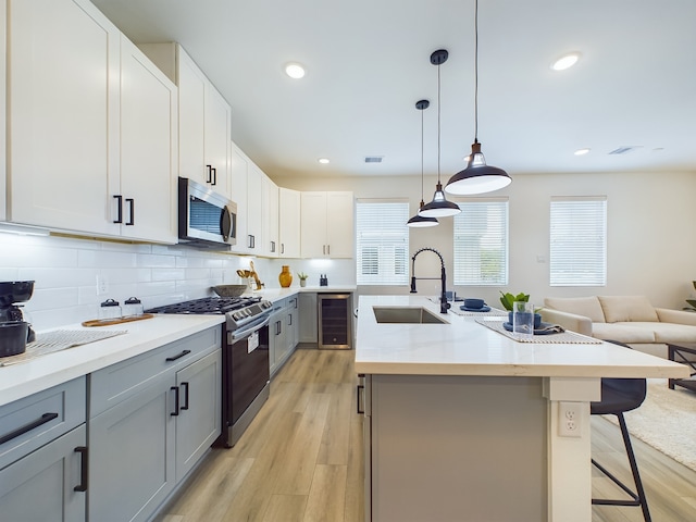 8317 Springwood Canyon Ln, Houston, TX 77055 - kitchen featuring stainless steel appliances, beverage cooler, gray cabinets, a breakfast bar area, and light wood-type flooring