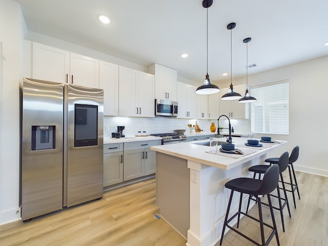 8317 Springwood Canyon Ln, Houston, TX 77055 - kitchen featuring stainless steel appliances, light wood-type flooring, light countertops, an island with sink, and backsplash