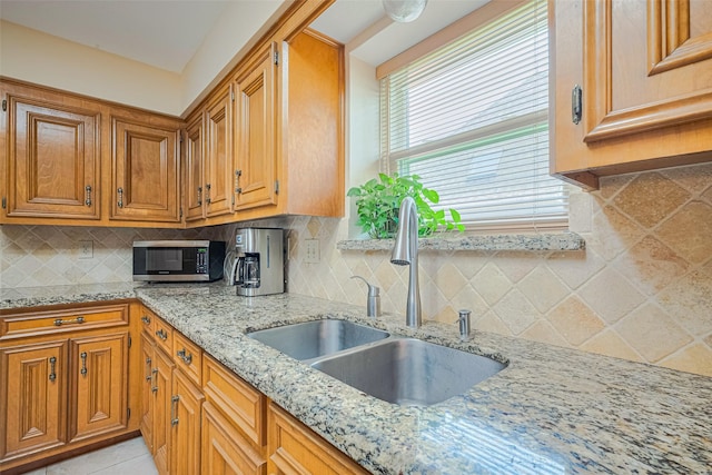 15435 Rio Plaza Dr, Houston, TX 77083 - kitchen with stainless steel microwave, light stone counters, and brown cabinets