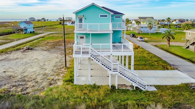 4018 6th St, Galveston, TX 77554 - rear view of property with covered porch, stairway, a balcony, a residential view, and a yard