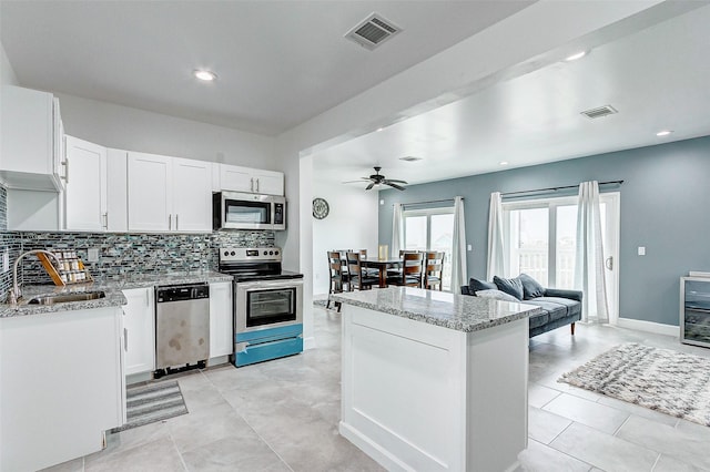 4018 6th St, Galveston, TX 77554 - kitchen featuring stainless steel appliances, tasteful backsplash, white cabinets, light stone countertops, and a ceiling fan