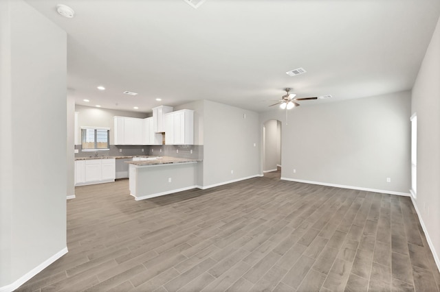 5096 Marcasca Dr, Katy, TX 77493 - unfurnished living room with light wood-type flooring, arched walkways, ceiling fan, and recessed lighting