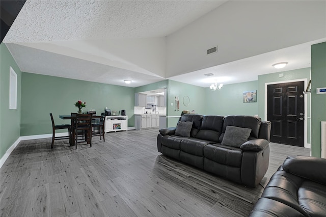 3606 Darling Ave, Pasadena, TX 77503 - living area with lofted ceiling, light wood finished floors, a chandelier, and a textured ceiling