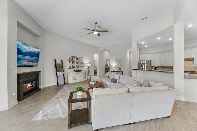 15519 Ponderosa Bend Dr, Cypress, TX 77429 - living room with ceiling fan, light wood finished floors, a glass covered fireplace, recessed lighting, and arched walkways