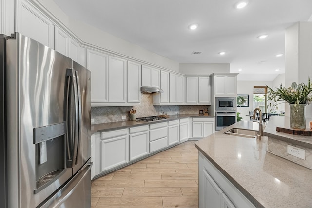 15519 Ponderosa Bend Dr, Cypress, TX 77429 - kitchen featuring stainless steel appliances, backsplash, under cabinet range hood, white cabinets, and light stone countertops