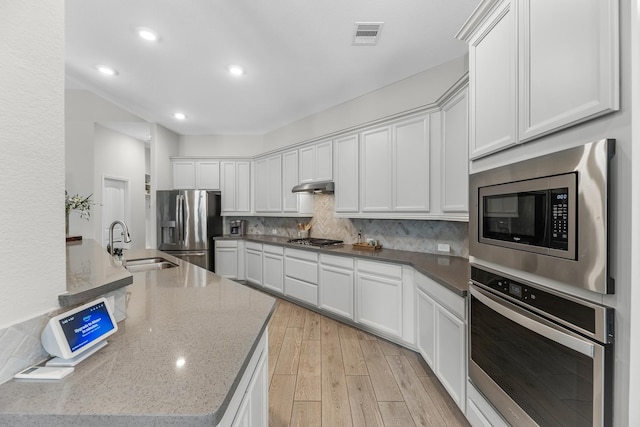 15519 Ponderosa Bend Dr, Cypress, TX 77429 - kitchen featuring stainless steel appliances, under cabinet range hood, backsplash, white cabinetry, and light wood-style flooring