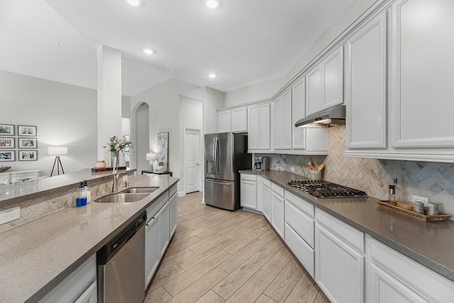 15519 Ponderosa Bend Dr, Cypress, TX 77429 - kitchen with appliances with stainless steel finishes, under cabinet range hood, arched walkways, backsplash, and recessed lighting