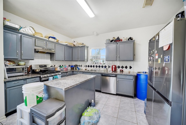 4014 Timber Cor, Houston, TX 77082 - kitchen with appliances with stainless steel finishes, under cabinet range hood, backsplash, a kitchen island, and gray cabinetry