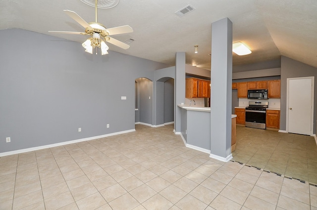 8747 Cypressbrook Dr, Houston, TX 77095 - kitchen with stainless steel stove, black microwave, lofted ceiling, arched walkways, and brown cabinetry