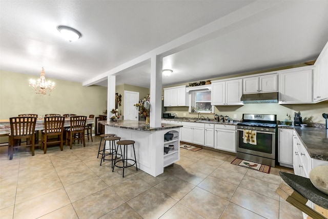 19757 Dorris Dr, Magnolia, TX 77355 - kitchen with stainless steel gas range oven, under cabinet range hood, a chandelier, white cabinets, and light tile patterned floors