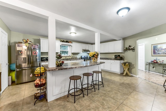 19757 Dorris Dr, Magnolia, TX 77355 - kitchen featuring stainless steel appliances, under cabinet range hood, a breakfast bar, white cabinetry, and dark stone counters