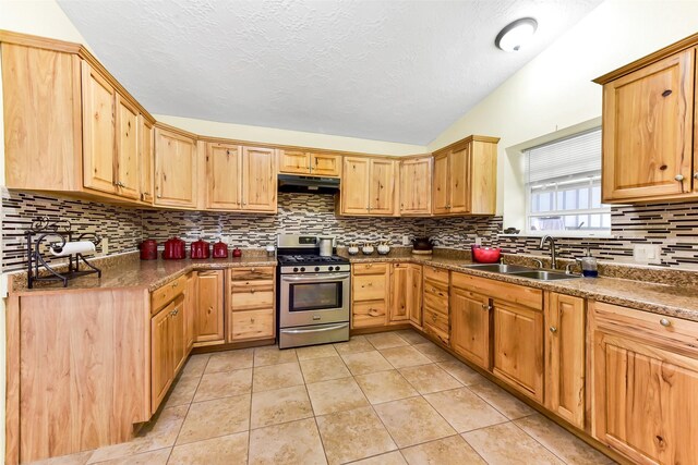 19757 Dorris Dr, Magnolia, TX 77355 - kitchen featuring gas range, lofted ceiling, decorative backsplash, light tile patterned floors, and under cabinet range hood