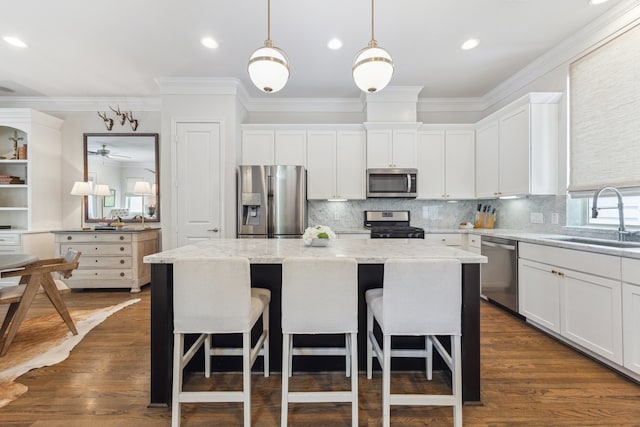 1010 W 24th St Unit N, Houston, TX 77008 - kitchen featuring stainless steel appliances, a kitchen island, a kitchen bar, white cabinets, and decorative backsplash