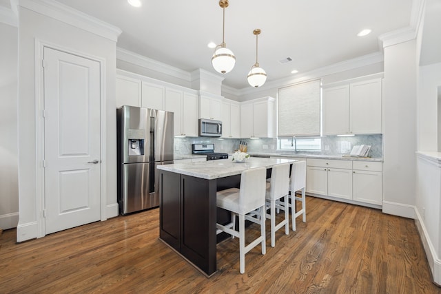 1010 W 24th St Unit N, Houston, TX 77008 - kitchen featuring appliances with stainless steel finishes, white cabinetry, a kitchen breakfast bar, a kitchen island, and tasteful backsplash
