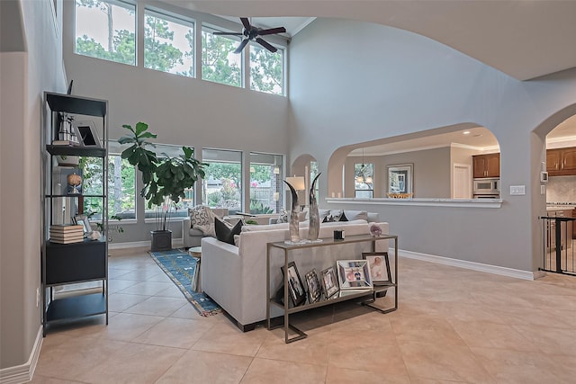 18315 Cape Lookout Way, Humble, TX 77346 - living room with a ceiling fan, arched walkways, healthy amount of natural light, light tile patterned floors, and a towering ceiling