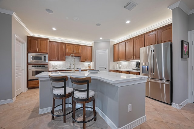 18315 Cape Lookout Way, Humble, TX 77346 - kitchen featuring appliances with stainless steel finishes, crown molding, a center island with sink, tasteful backsplash, and light tile patterned flooring