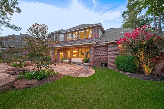 18315 Cape Lookout Way, Humble, TX 77346 - back of house featuring an outdoor living space, brick siding, a patio area, a lawn, and a shingled roof