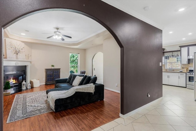 5343 Oak Cove Dr, Houston, TX 77091 - living room with arched walkways, crown molding, a ceiling fan, a glass covered fireplace, and light tile patterned floors