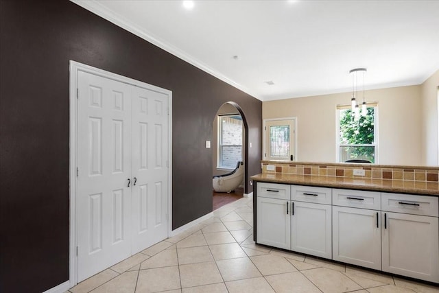 5343 Oak Cove Dr, Houston, TX 77091 - kitchen with light tile patterned floors, ornamental molding, decorative light fixtures, arched walkways, and white cabinetry