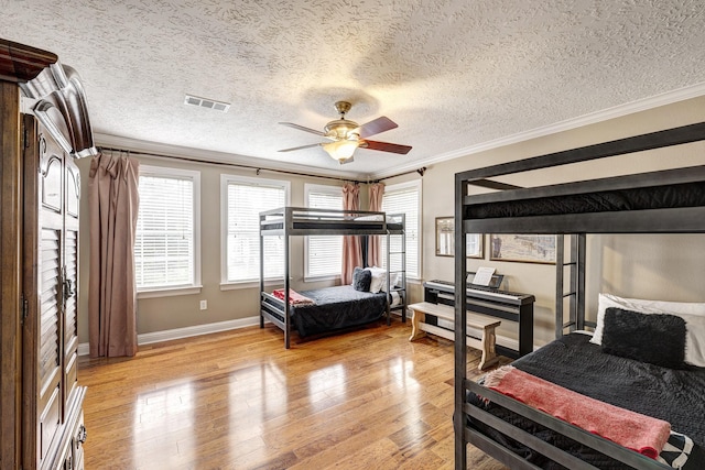 2120 Gostick St, Houston, TX 77008 - bedroom featuring ornamental molding, light wood-style flooring, a textured ceiling, and a ceiling fan