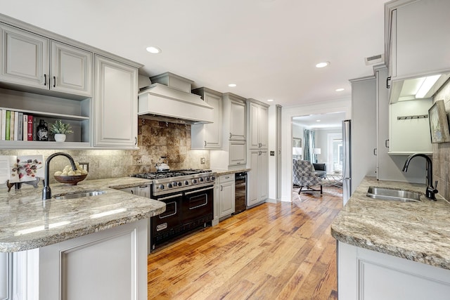 2120 Gostick St, Houston, TX 77008 - kitchen featuring stainless steel appliances, wine cooler, custom range hood, light wood-style flooring, and backsplash