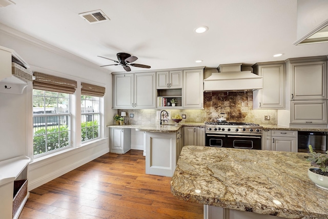 2120 Gostick St, Houston, TX 77008 - kitchen with range with two ovens, premium range hood, light wood-style floors, light stone countertops, and tasteful backsplash
