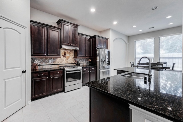 2302 Lakecrest Gardens Dr, Katy, TX 77493 - kitchen with appliances with stainless steel finishes, under cabinet range hood, backsplash, dark stone counters, and light tile patterned floors