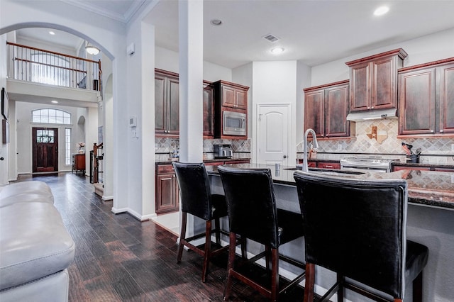 2302 Lakecrest Gardens Dr, Katy, TX 77493 - kitchen with stainless steel appliances, a kitchen breakfast bar, tasteful backsplash, dark wood-type flooring, and crown molding