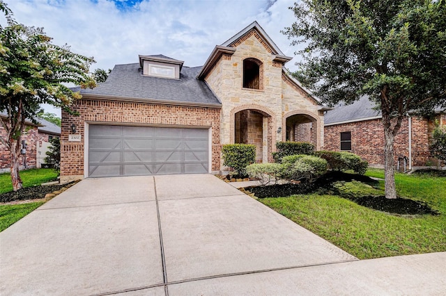 2302 Lakecrest Gardens Dr, Katy, TX 77493 - french country home featuring brick siding, driveway, an attached garage, a front yard, and stone siding