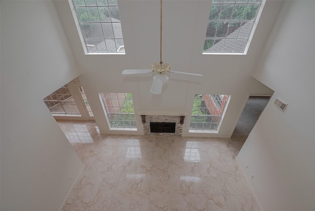 1615 Monvale Ln, Sugar Land, TX 77479 - unfurnished living room featuring marble tiled floors, a towering ceiling, ceiling fan, and a fireplace