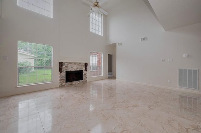 1615 Monvale Ln, Sugar Land, TX 77479 - unfurnished living room featuring marble tiled floors, a high ceiling, ceiling fan, plenty of natural light, and a fireplace